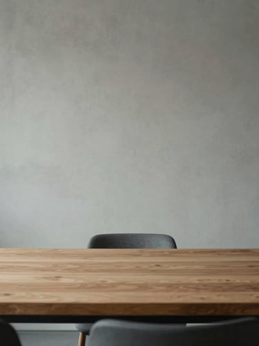 Weitwinkel-Aufnahme eines minimalistischen Konferenzraums in Wiesbaden bei diffusem Tageslicht, strukturierte Betonwand im Hintergrund, leerer Massivholztisch im Vordergrund, keine Personen.