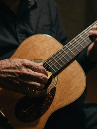 Close-up of calloused hands sliding a brass slide down the neck of a vintage resonator guitar, low-key warm spotlight, deep shadows, dust particles in the air