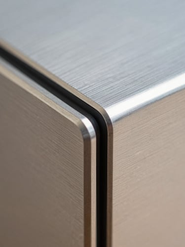 Extreme macro close-up of brushed titanium device chassis edges reflecting sharp, diffuse architectural daylight, clean geometric lines, high-end product photography style.