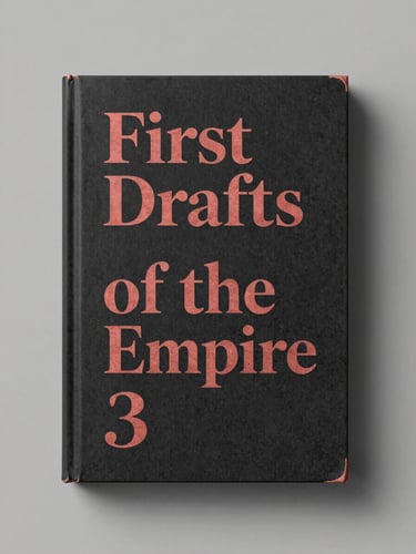 Straight-on physical book mockup of 'First Drafts of the Empire', showing a dark charcoal cover with dusty cadmium red ink accents.
