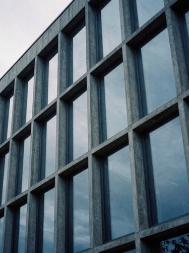 Extreme close-up of a modern concrete and glass facade in Luxembourg under cool overcast daylight, sharp architectural lines, medium format film