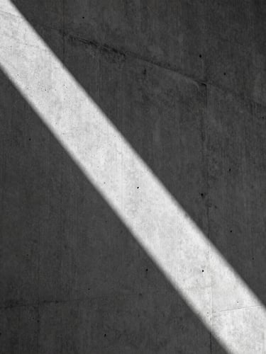 Abstract architectural macro detail of raw board-formed concrete texture, sharp diagonal geometric shadow, high-contrast black and white, cold clinical silence.