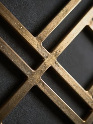 Macro close-up of a geometric metal lattice panel with clean laser-cut edges, metallic gold accents reflecting soft architectural light, dark graphite background