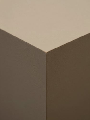 Close-up straight-on detail of a finished work piece — precise edges and controlled studio lighting, muted warm-toned surface, no competing background elements, full-frame crop
