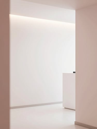 Serene minimalist clinic interior with soft warm lighting, white walls, and elegant dusty rose details, architectural lines