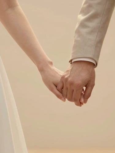 Hands of a bride and groom gently joined together, showing elegant wedding details, soft warm golden light, romantic and respectful atmosphere
