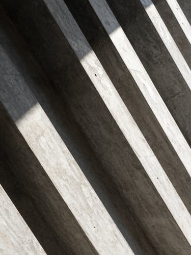 Abstract architectural concrete lines with sharp diagonal shadows under natural daylight, conveying structure and clarity.