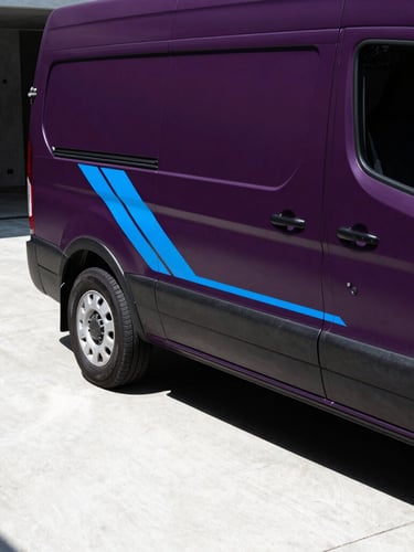 Close-up of a matte dark purple utility van with sharp electric blue geometric branding lines, parked in a modern concrete courtyard, dramatic high-contrast lighting