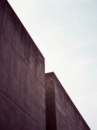 Minimalist architectural lines, sharp concrete angles against a bright sky, dramatic deep mauve shadows, high-contrast editorial composition