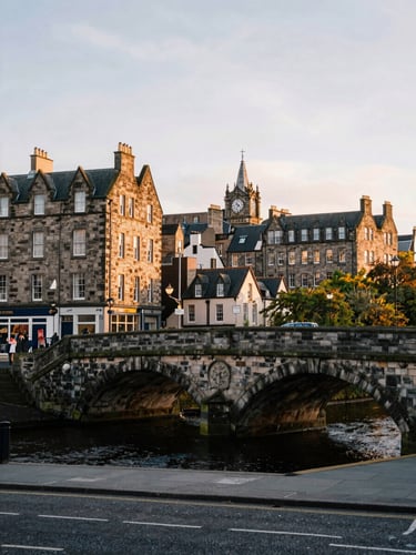 Quiet streetscape of Stockbridge Edinburgh, historic stone bridge over water, soft golden hour lighting, muted historic tones.