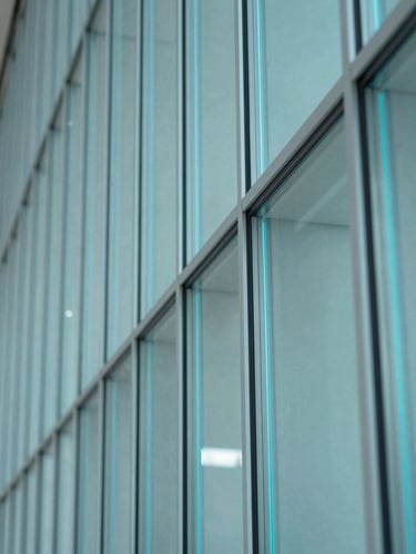 Macro detail shot of architectural glass edge refracting cyan light, subtle embedded electronics visible, crisp focus, architectural interior photography, 35mm.