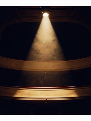 Low-angle dramatic stage photography of a single empty theater balcony bathed in a warm gold spotlight, deep navy shadows, 35mm film.