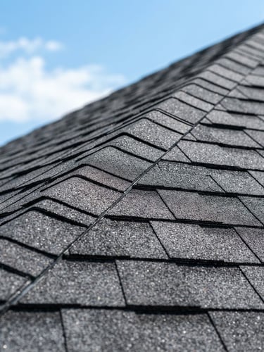 Close-up of clean residential asphalt shingles against a bright North Texas sky, crisp focus, professional editorial photography