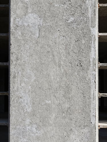 Extreme close-up of raw concrete formwork texture on a building facade, north-facing daylight revealing aggregate grain and fine surface relief, no shadows obscuring detail, tightly framed with no decorative elements