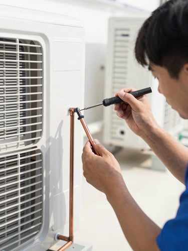 Close-up of a professional technician soldering copper pipes on an air conditioning installation, bright natural daylight, high-contrast industrial aesthetic.
