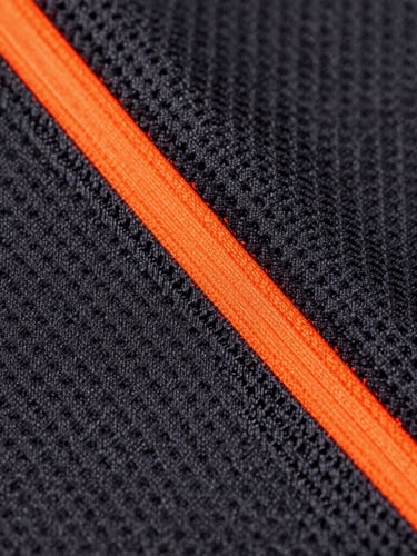 Macro photograph of high-contrast athletic fabric weave, sharp neon-orange stitching detail, dark charcoal technical mesh background, professional studio lighting, 85mm lens