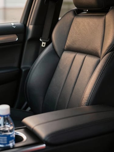 Macro detail of a pristine black leather seat inside a luxury SUV, corporate amenities like premium bottled water in the console, soft ambient golden lighting.