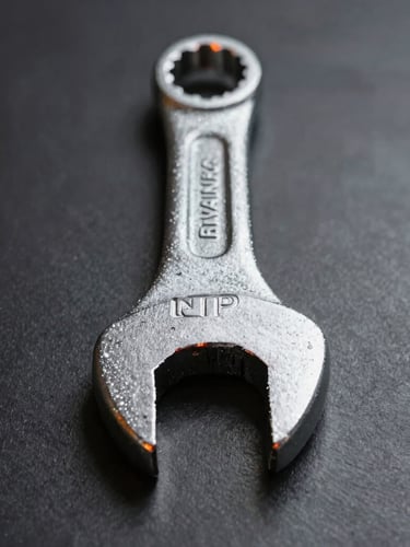 Straight-on structural profile of a heavy-duty forged steel wrench on a dark metallic background, sharp directional studio lighting with safety-orange highlights