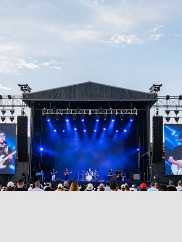 Wide environmental shot of a massive live event stage in Golden Colorado, heavy royal blue backlighting, technical rigging visible, crisp resolution.