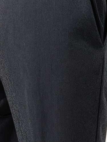 Extreme close-up of premium woven trouser fabric filling the entire frame, shot flat under bright even studio lighting — tight weave structure visible thread by thread, deep charcoal grey fabric, sharp focus on texture and yarn interlace, no human subject, no background, pure fabric surface documentary