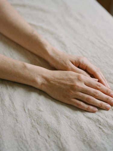A quiet close-up of hands resting in repose on textured linen, soft overcast daylight casting gentle shadows, warm minimalist aesthetic, 35mm film texture