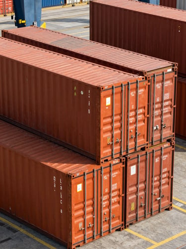 High-angle architectural shot of massive orange shipping containers stacked at a modern industrial port terminal under crisp daylight