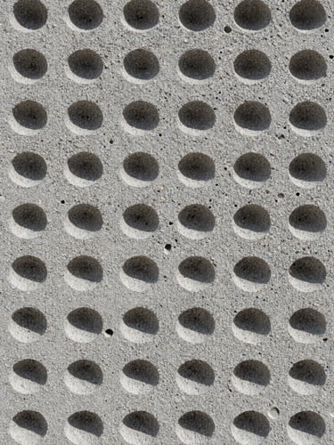 Macro technical photography of a concrete foam cell matrix, showing the uniform air bubble structure inside the gray concrete, harsh direct sunlight highlighting the porous texture, straight-on technical shot.