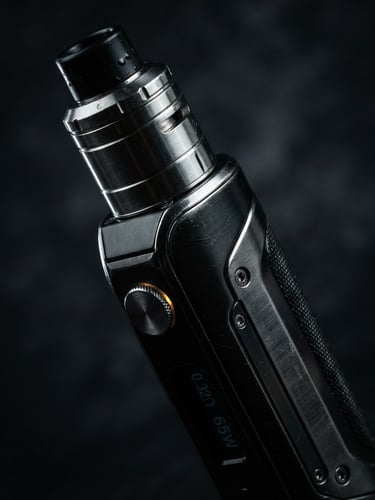 Macro close-up of a sleek metallic vape mod, sharp rim lighting highlighting the brushed steel edges, dark studio background, deep shadows, 3:4 aspect