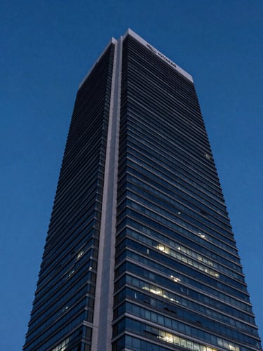 Low-angle dramatic twilight shot of a modern skyscraper in Balneário Camboriú, clean geometric lines against a deep blue hour sky, negative space on the left.