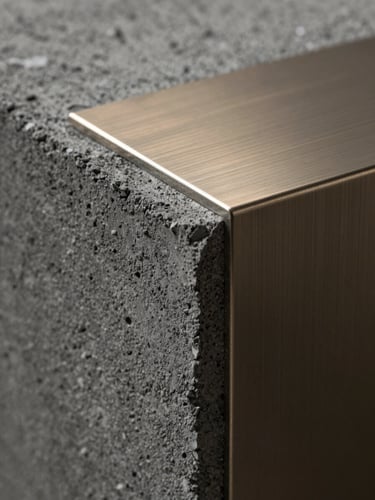Extreme macro close-up of premium building materials, raw dark concrete meeting brushed champagne steel, high-contrast side lighting, architectural texture.