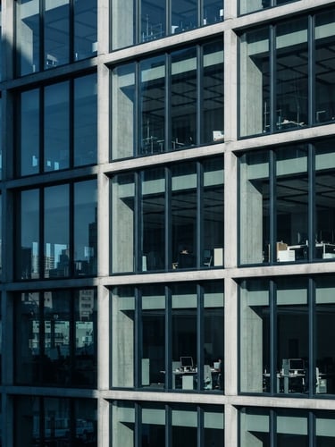 Architectural crop of a modern concrete and glass corporate office facade, sharp morning light, deep slate shadows, cool editorial style, 35mm lens