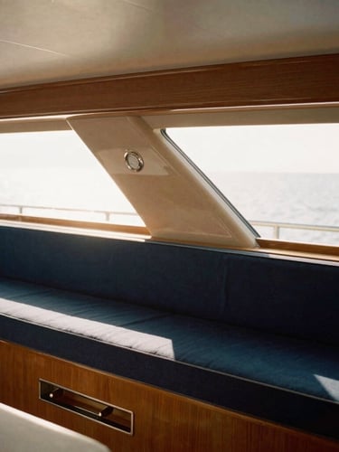 Close-up of the elegant yacht interior, warm polished wood, soft natural sunlight streaming through deck hatches, minimalist luxury cabin styling, 35mm film look.