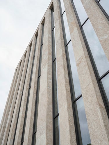 Extreme wide-angle architectural composition of a limestone facade under diffused overcast daylight, clean glass lines, minimalist luxury, negative space on the left