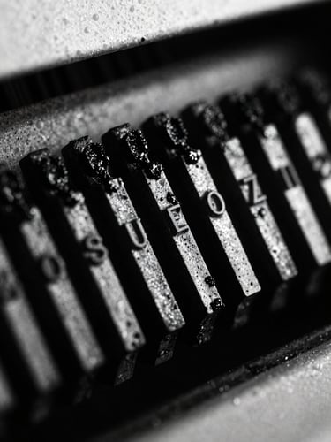 Macro close-up of a printing press metal type blocks covered in black ink, deep shadows, stark high-contrast lighting