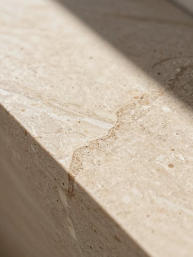 Close-up macro shot of premium cream travertine vein texture, warm natural desert sunlight, soft architectural shadows, editorial layout
