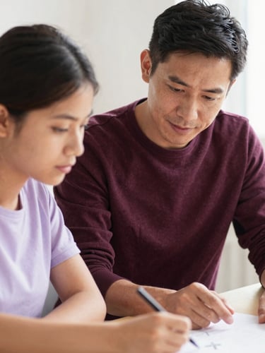A candid medium shot of a mentor guiding a young adult through a project, warm daylight, soft lavender tones, shallow depth of field, authentic focus