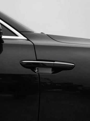 Desaturated minimalist editorial photography of a polished black luxury sedan door handle, sharp shadows, overcast daylight, crisp 50mm lens
