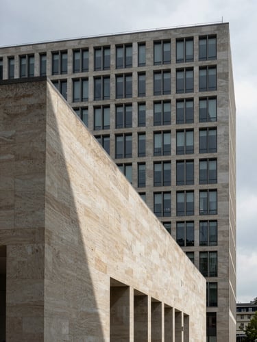 Wide architectural facade of a modernist Milan office building, stone cladding detail in foreground left, deep shadow lines cutting across the surface, overcast diffuse daylight, no people