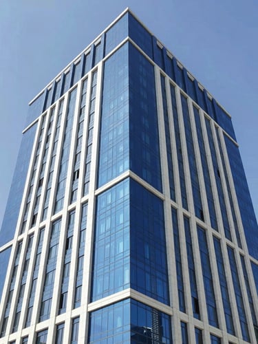 Low-angle architectural shot of a modern corporate building in Sana'a with premium blue cladding and structural glass, bright daylight, clear sky, realistic