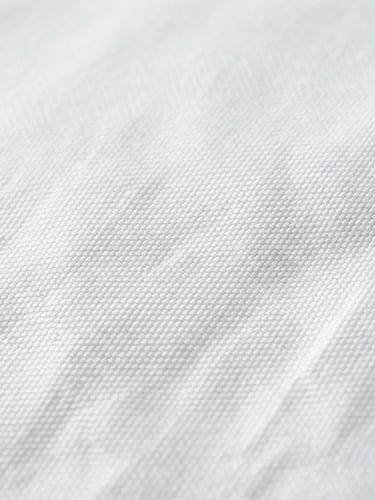 Macro photograph of crisp white high-thread-count hotel bedsheets, sharp textile weave, bright neutral daylight, clean slate gray shadows