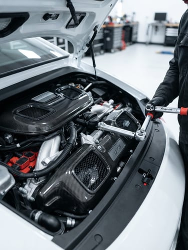 Sharp macro shot of a clean Porsche engine bay under high-key white workshop lighting, carbon fiber covers, torque wrench visible on the side, crisp depth of field, 50mm lens