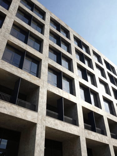 Low-angle architectural shot of a modern concrete and steel commercial building facade in Accra, bright midday sun, sharp shadows, 35mm