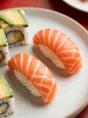 Overhead macro shot of fresh salmon nigiri and avocado rolls on a clean ceramic plate, bright natural light, rich red accents