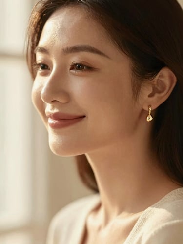 Soft-focus portrait of a woman smiling, wearing delicate gold earrings catching warm window light, elegant and modern styling.