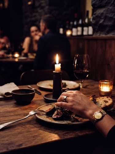 Moody editorial photography of a low-key candlelit table setup, warm amber glow, rich plum shadows, high contrast, 35mm film style