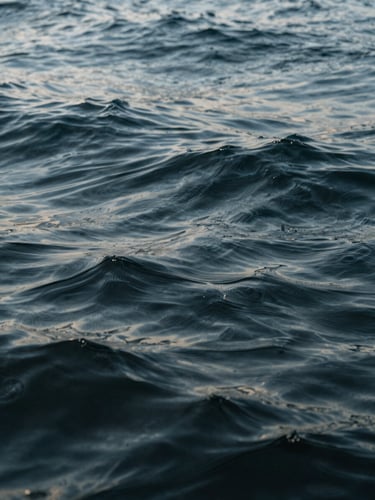 Abstract close-up texture of deep ocean water with gentle ripples, soft natural lighting, editorial composition, calm luxury aesthetic