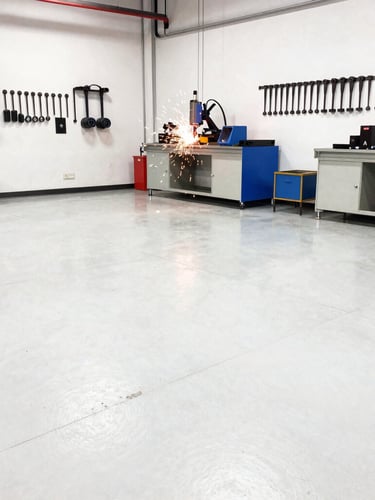 Wide-angle view of a bright, high-contrast fabrication workshop, sparks flying from a welding station in the background, clean concrete floor, tools arranged neatly on walls