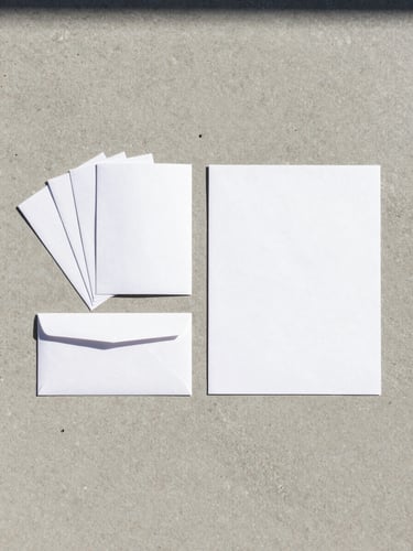 Wide shot of a finished printed brand identity system laid flat on a pale concrete surface under cool daylight — stationery, folded brochure, and envelope fanned left, generous negative space to the right