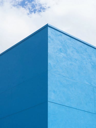 Sharp architectural angle of a modern commercial building exterior with clean electric blue coatings under bright Florida sun