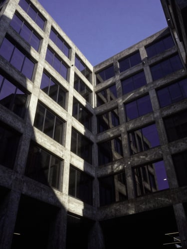 Low-angle dramatic architectural photograph of a brutalist-inspired concrete corporate complex, sharp geometric lines, royal purple sky reflection in glass facade, deep shadows